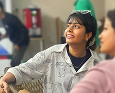 A joyful girl in a white shirt with glasses perched on her head, her gaze directed to the left of the photo