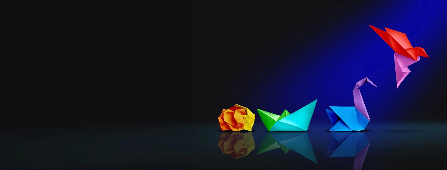A group of colourful origami birds and boats sit on a blue background.
