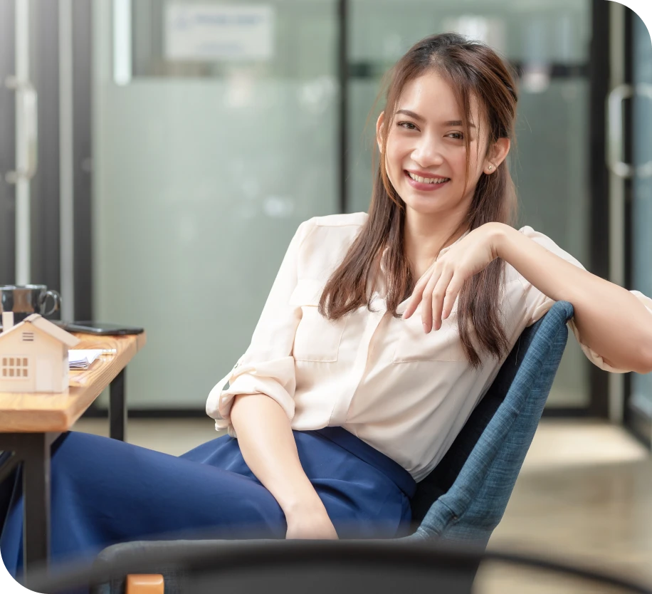 A female sitting sideways on a chair, facing the camera with a radiant smile. 