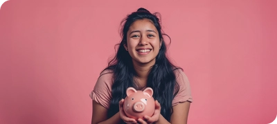 A girl holding a piggy bank in front of a pink background..