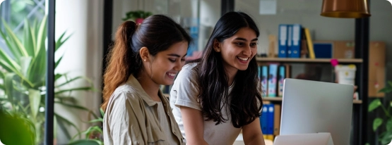 Two women working on a laptop in an office.