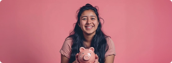 A girl holding a piggy bank in front of a pink background.